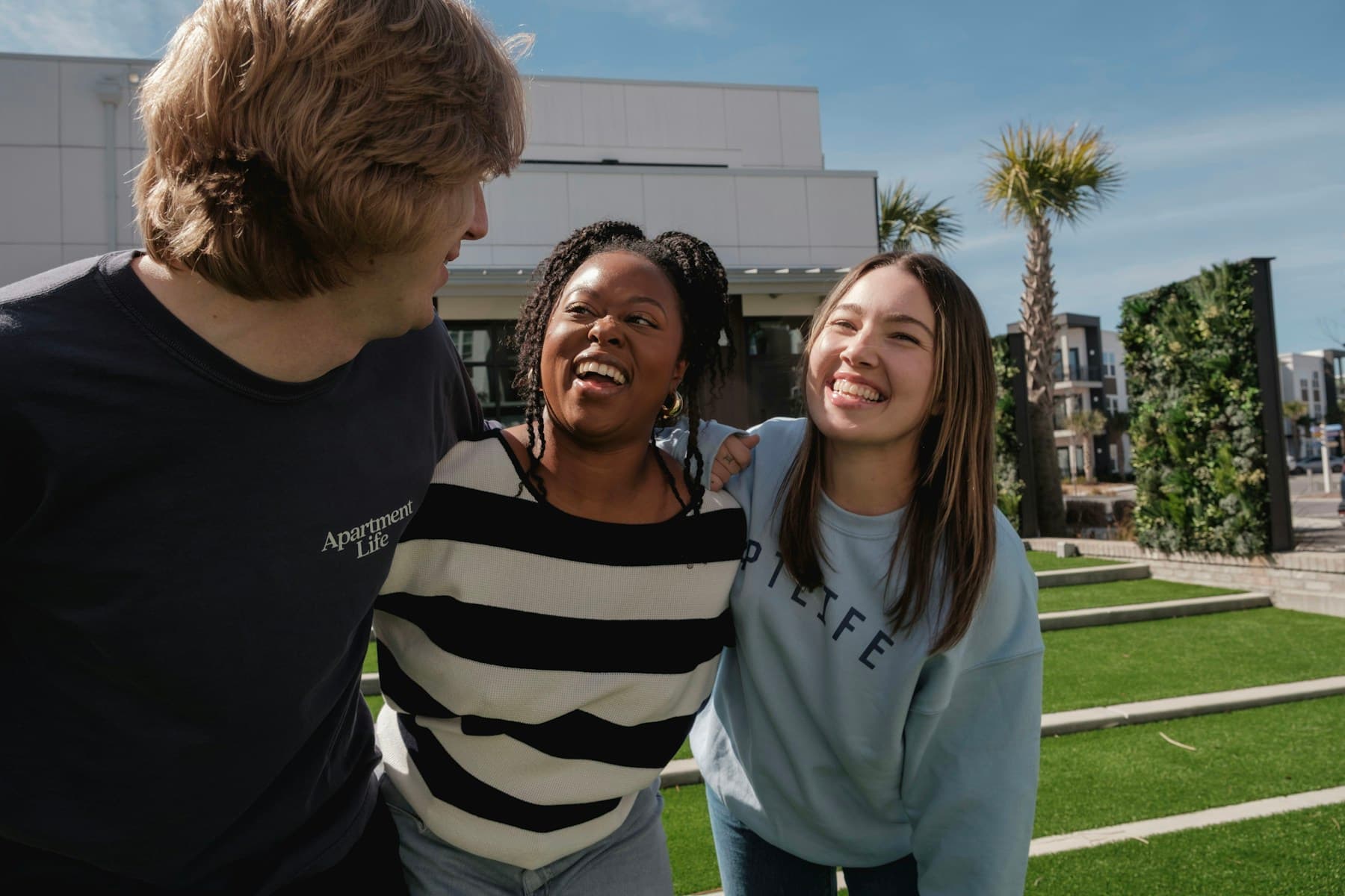 Three friends laughing together outdoors.